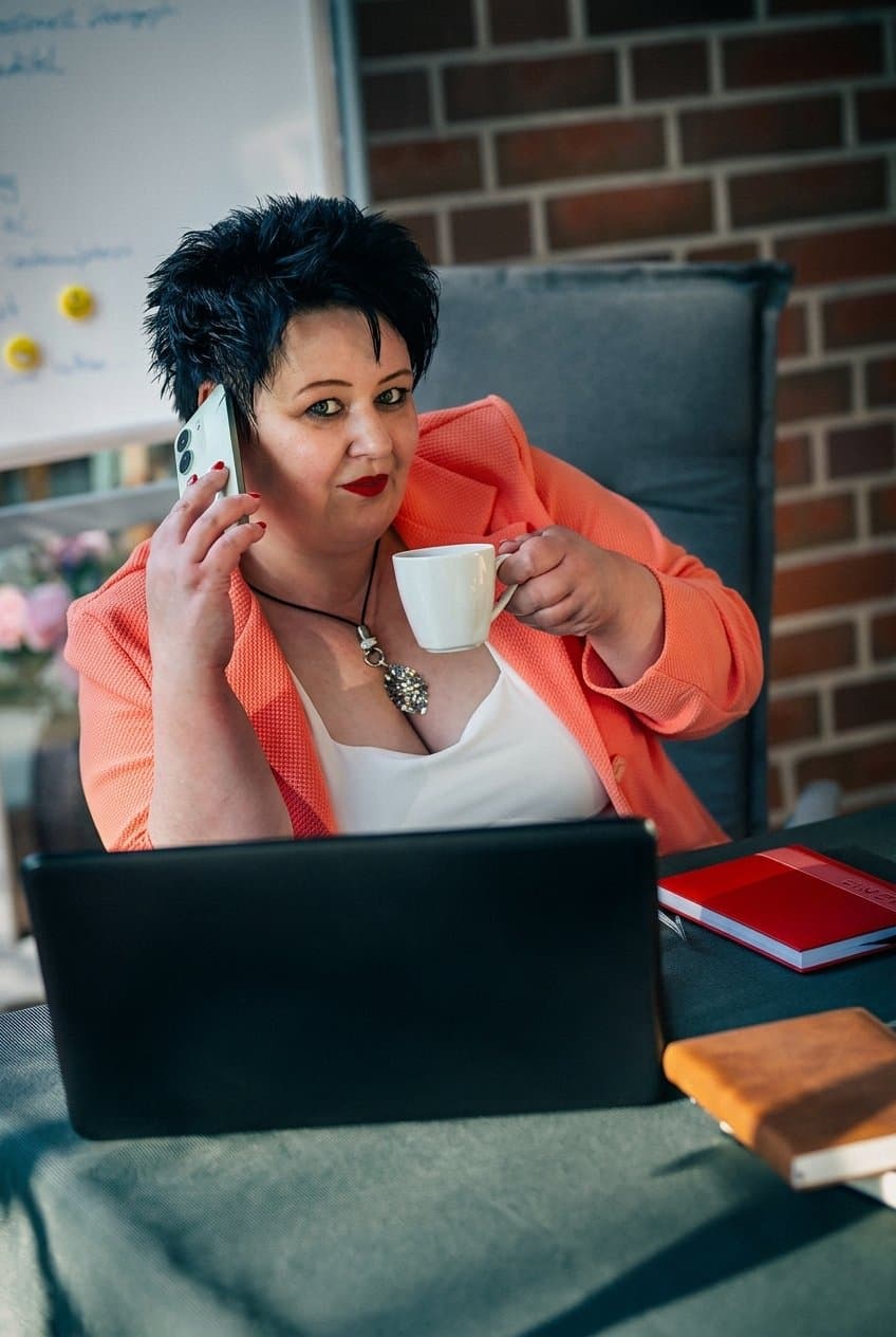 Nicole Lümken mit Kaffee und Telefon am Laptop