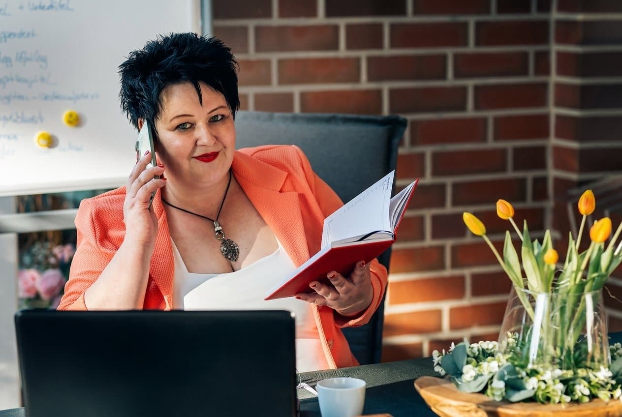 Nicole Lümken am Schreibtisch — telefonierend, mit Planer in der Hand
